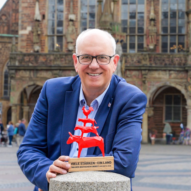 Foto von Andreas Bovenschulte mit einer Figur der Bremer Stadtusikanten
