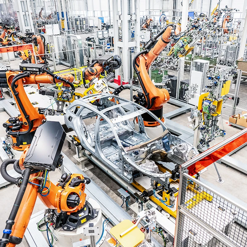 Roboterarme montieren in einer Fabrik verschiedene Teile an eine Fahrzeugkarosserie.