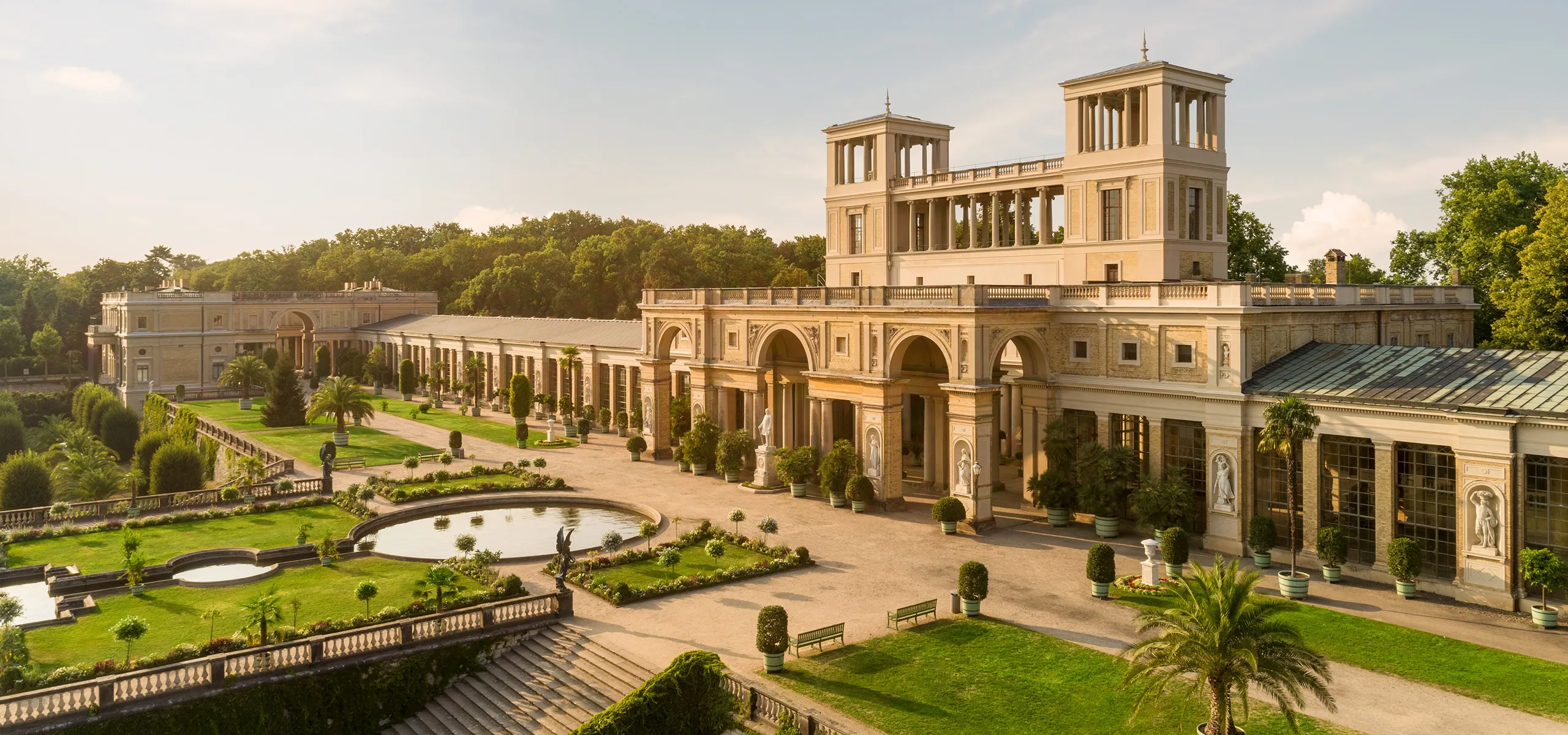 Ein imposantes Schloss mit mediterran anmutender Bepflanzung.