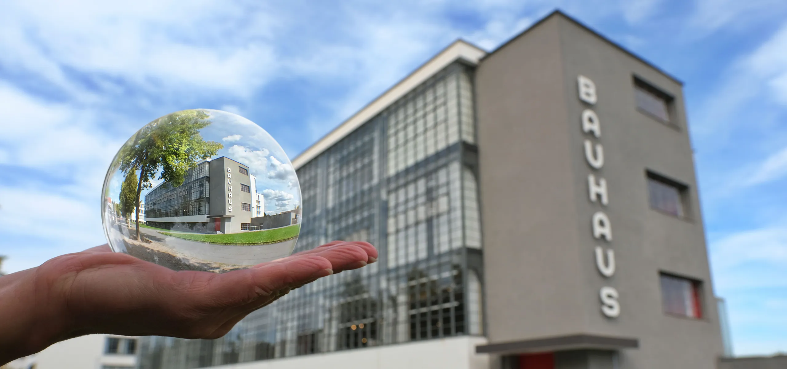 Ein graues Gebäude mit vielen Fenstern, dran der Schriftzug 'Bauhaus'.