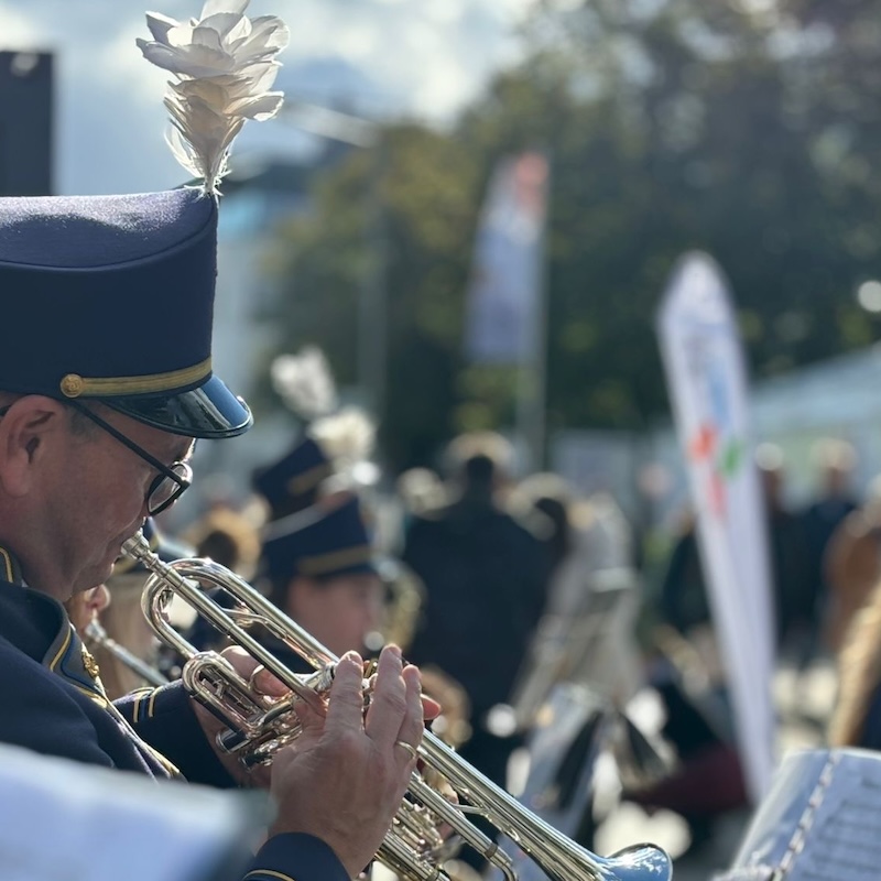Ein Musiker in bunter, blau-weißer Uniform spielt Trompete.