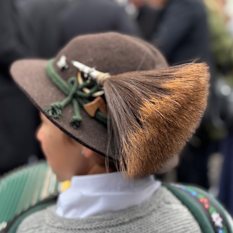 Ein traditioneller grauer Hut aus Filz mit einem pinselartigen Dekorationsstück.