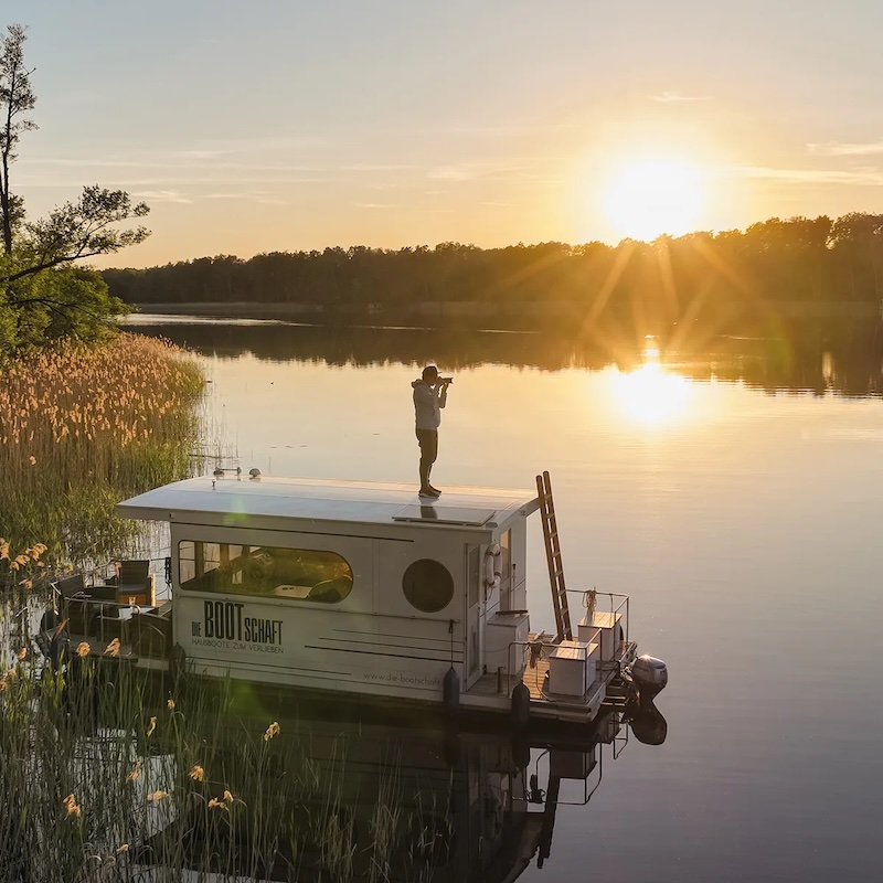 Ein Hausboot auf einem See in Brandenburg in der Abendsonne.