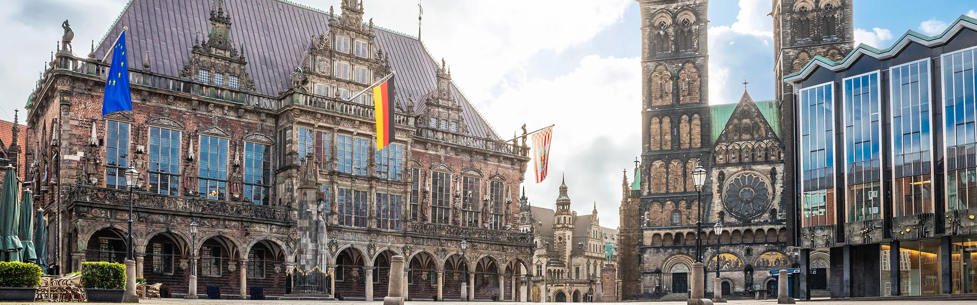 Das beflaggte historische Rathaus und davor der Roland. Rechts der St. Petri Dom und das Gebäude der Bremischen Bürgerschaft.