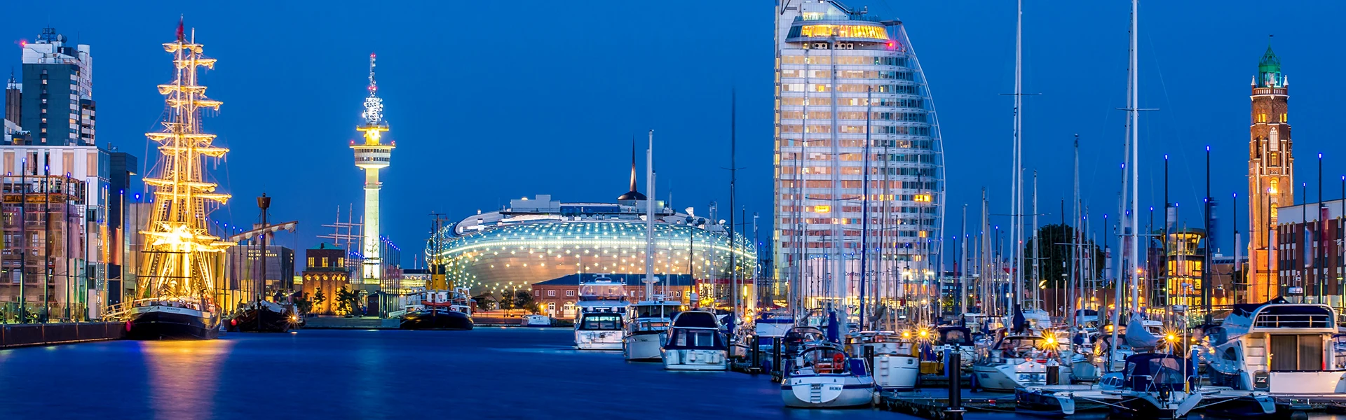 Die Skyline von Bremerhaven bei Nacht, von links nach rechts der hell erleuchtete Funkturm, das stimmungsvoll inszenierte Klimahaus und das in den Fenstern erleuchtete Hotel Sail City.