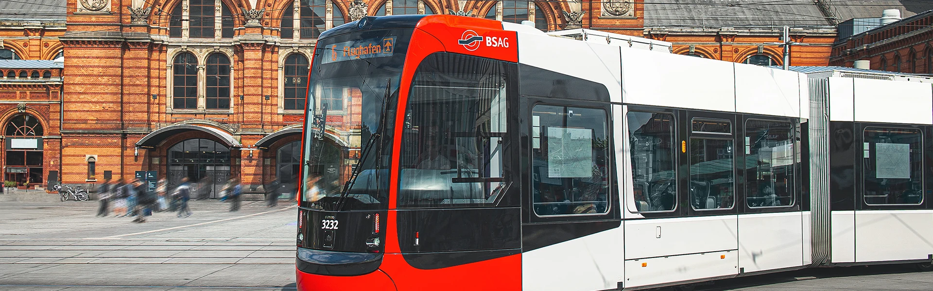 Eine Straßenbahn mit Ziel 'Flughafen' biegt vor dem Bremer Hauptbahnhof links ab.
