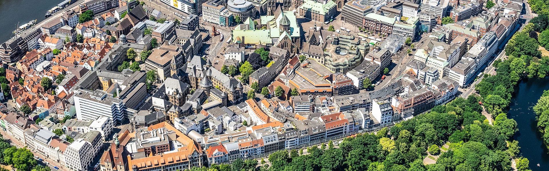 Die Bremer Innenstadt von oben. Viele bunte Dächer, am Rande die grünen Wallanlagen.