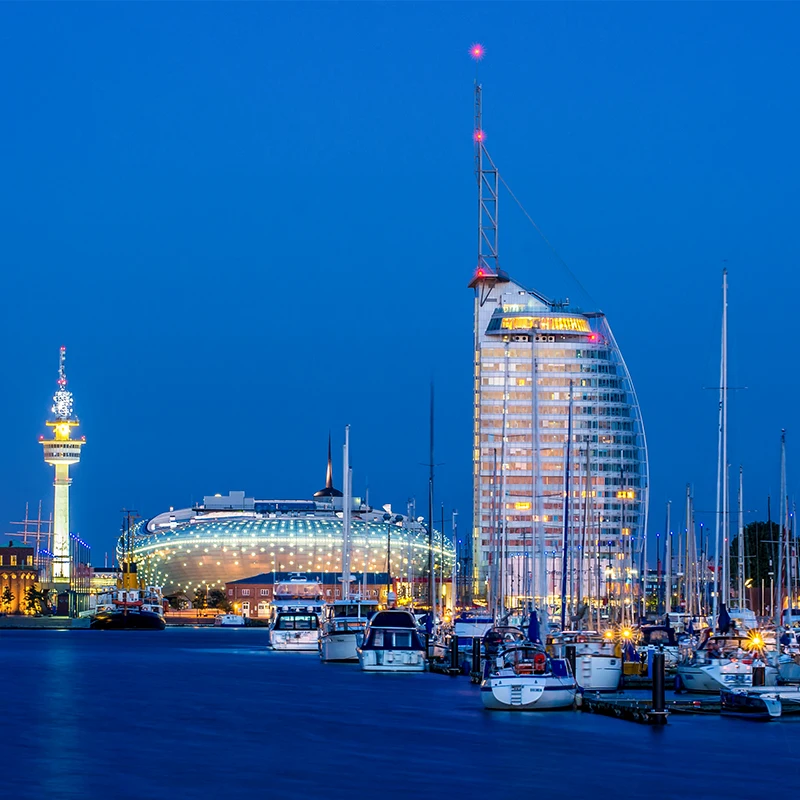Eine Nachtaufnahme der Skyline von Bremerhaven zeigt den Funkturm, das Klimahaus und das Hotel Sail City.