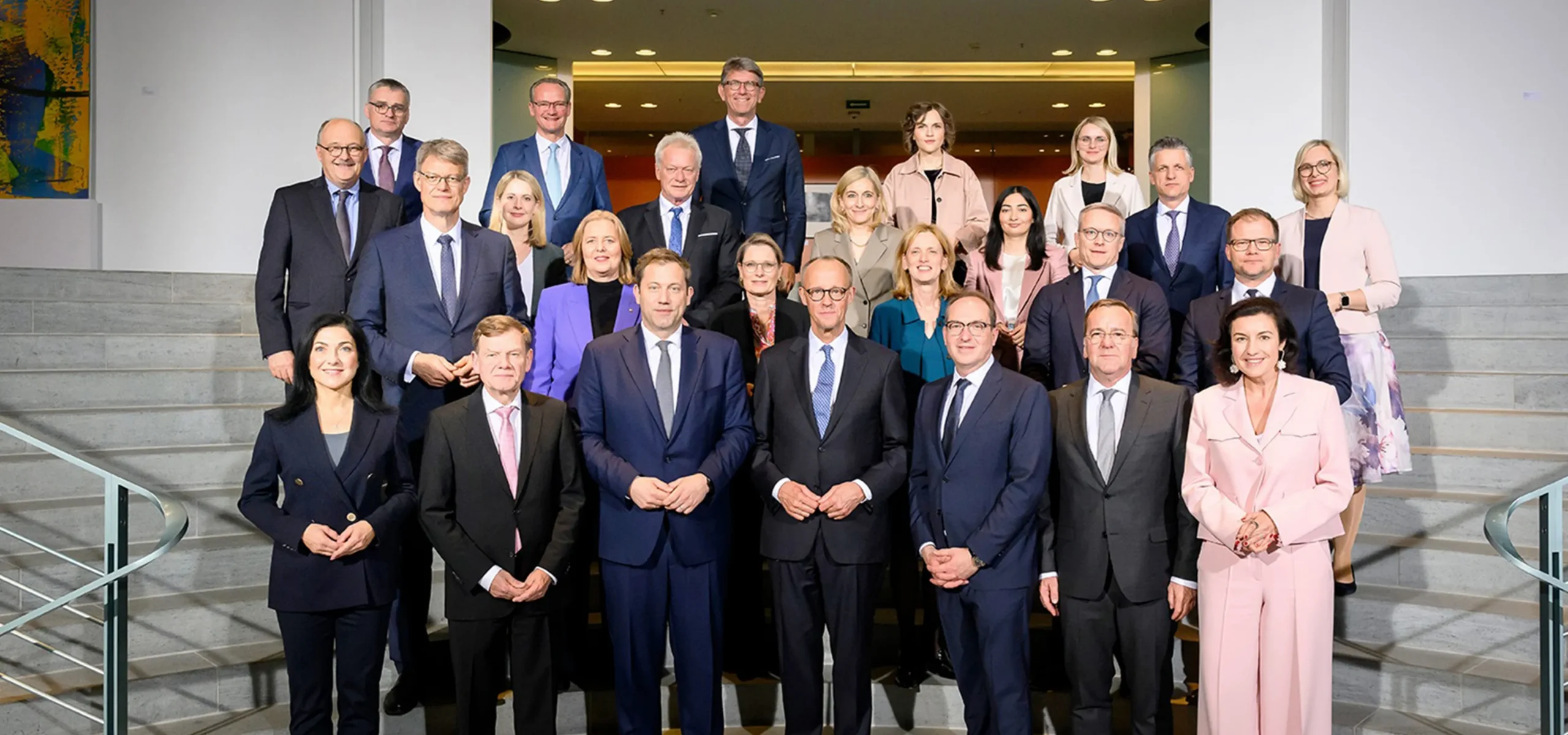 Viele wichtige Menschen auf einem Gruppenbild. Die Männer in Anzug und Krawatte, die Frauen in bunten Kostümchen.