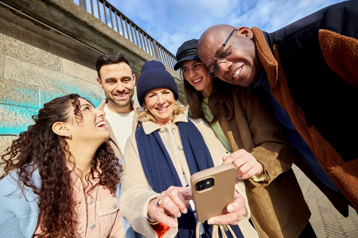 Fünf Personen lächeln in die Handykamera für ein Selfie
