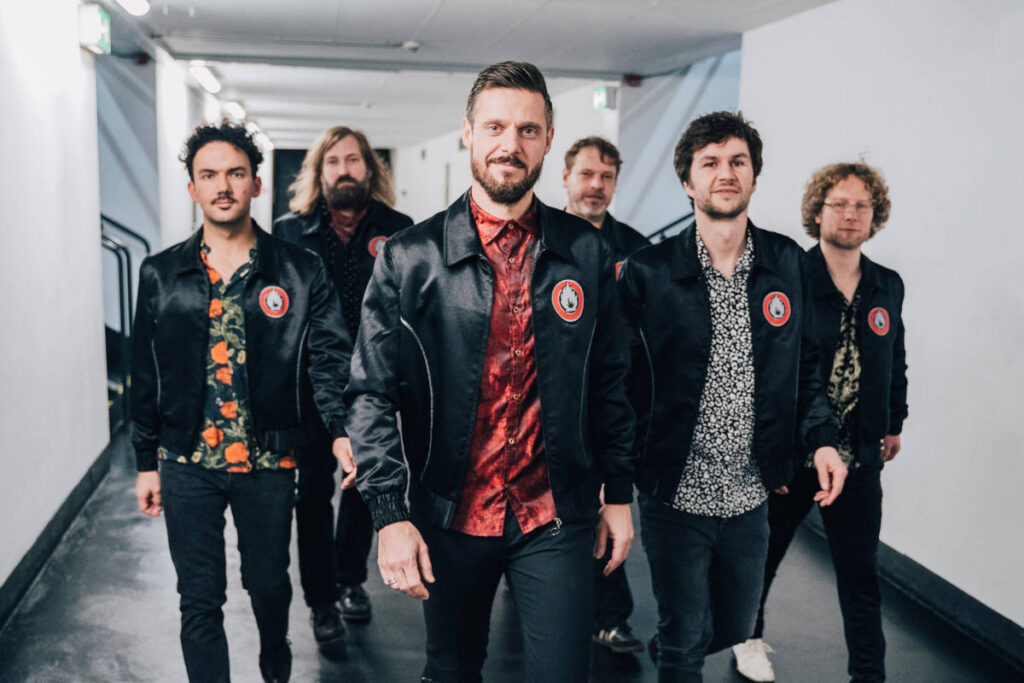 Die Mitglieder der Band Afterburner schreiten dynamisch einen Gang entlang.