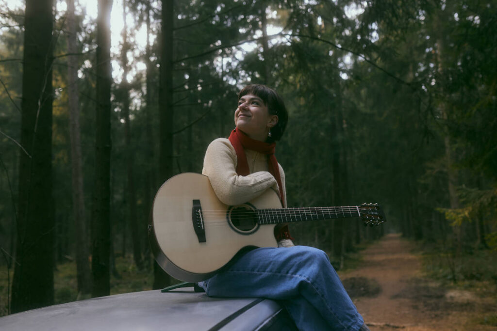Eine Sängerin mit Gitarre im Wald.